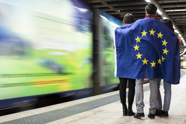 Jugendliche am Bahnhof mit EU-Flagge